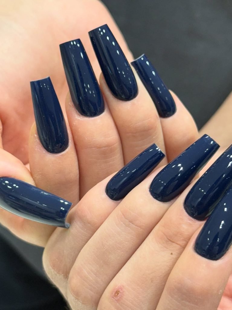long glossy navy blue square shaped nails displayed on both hands   