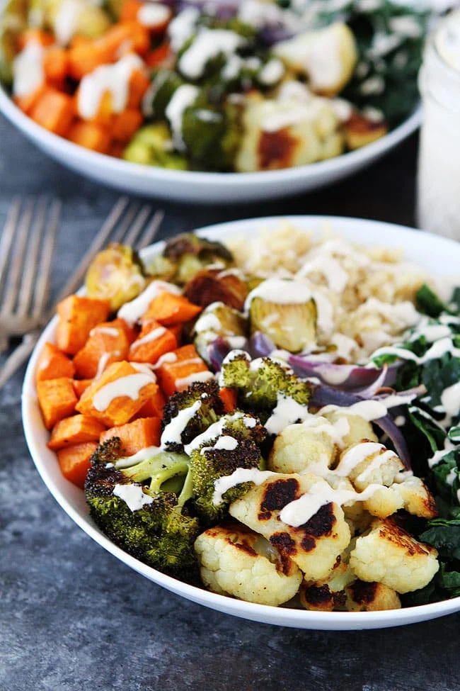 roasted vegetable quinoa bowl topped with cauliflower, broccoli, sweet potatoes, and creamy tahini sauce