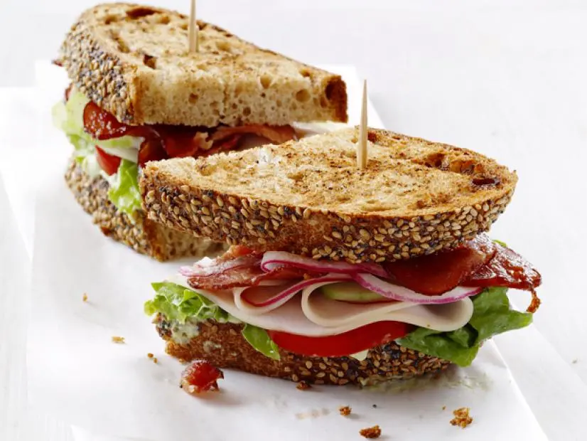 turkey club sandwich with bacon, lettuce, tomato, and avocado on seeded bread