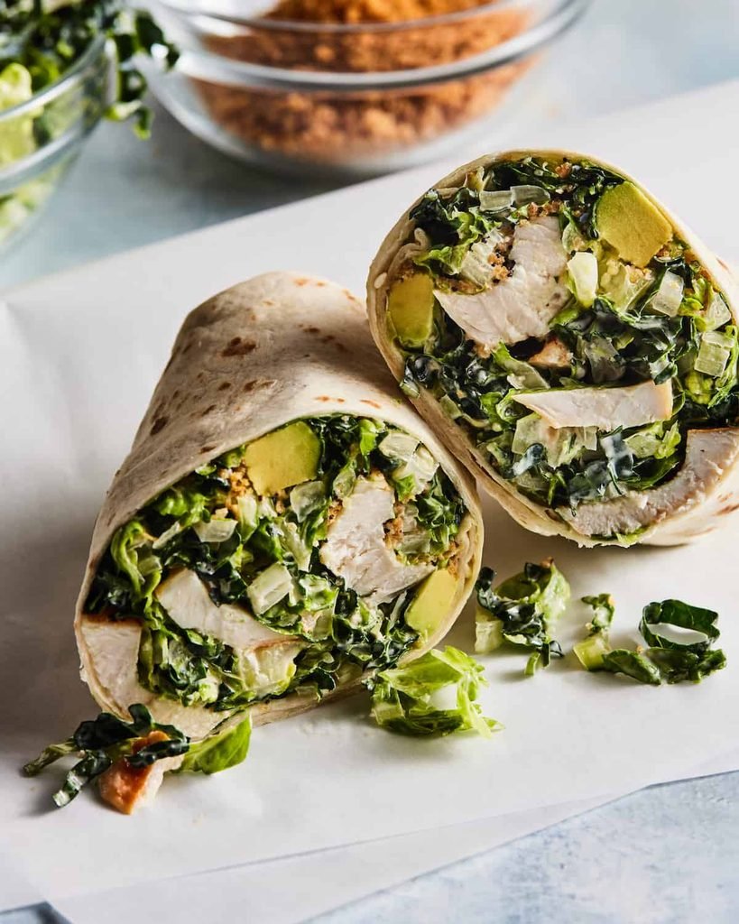 chicken caesar salad wrap sliced in half showcasing lettuce and avocado filling