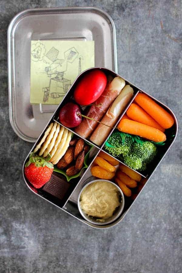 charcuterie bento box filled with rolled meats, carrots, crackers, nuts, and fresh fruit