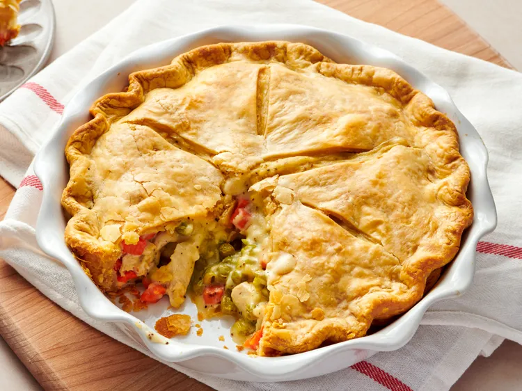 golden brown chicken pot pie with a slice cut out revealing vegetable filling   