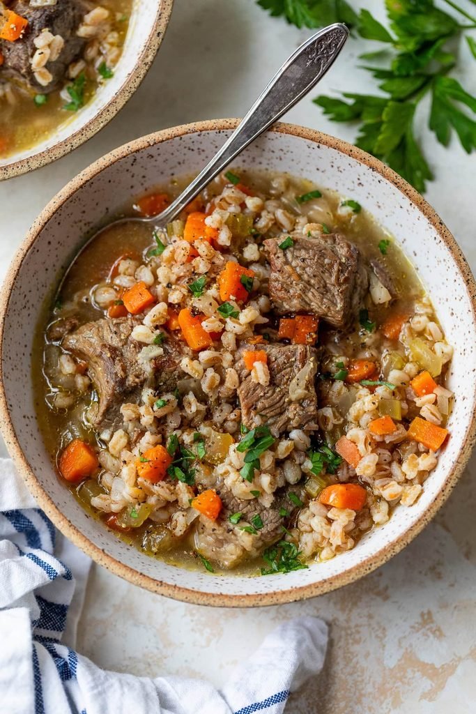 hearty beef and barley soup with chopped carrots in a ceramic bowl   