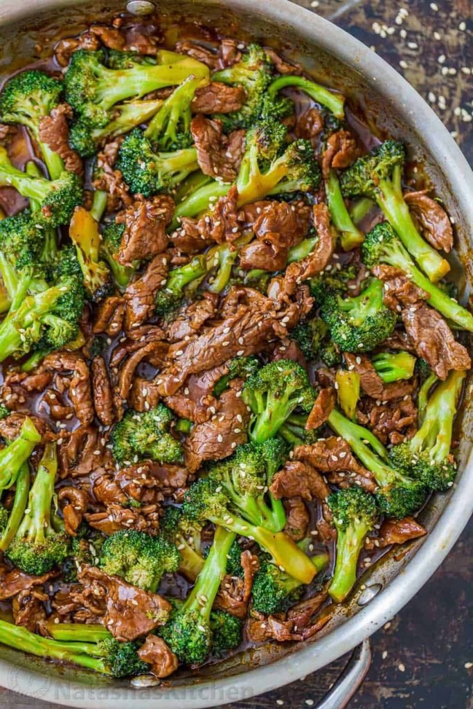 beef and broccoli stir fry in a savory brown sauce inside a large skillet   