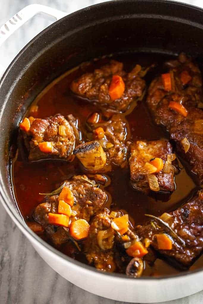 tender braised short ribs simmered with carrots in a dutch oven   