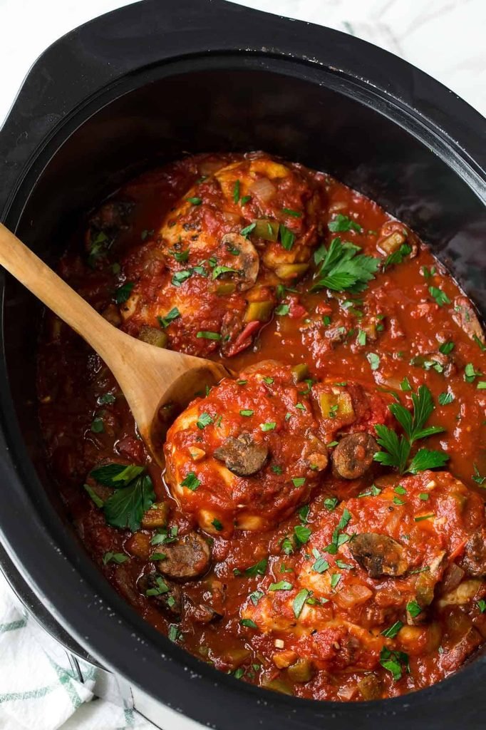 chicken cacciatore cooking in rich tomato mushroom sauce inside a slow cooker   