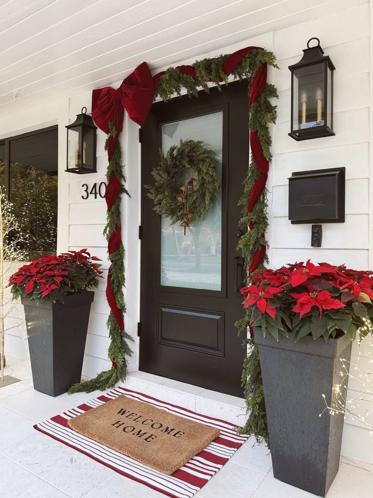 modern white porch with dark front door red velvet bows and poinsettias   