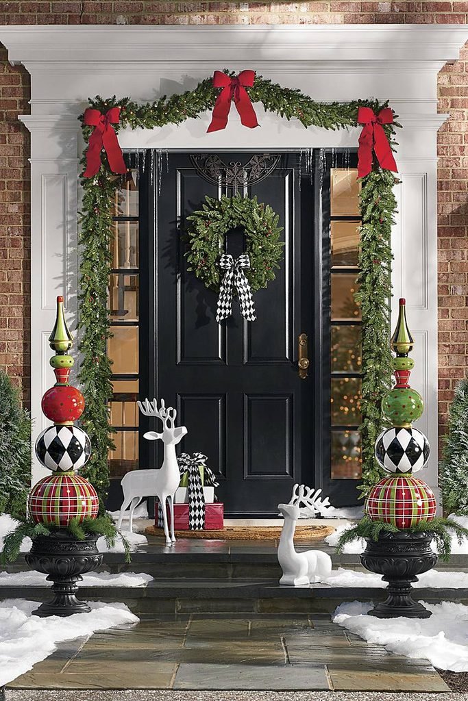 front porch entry with christmas garland oversized topiary ornaments and deer statues   