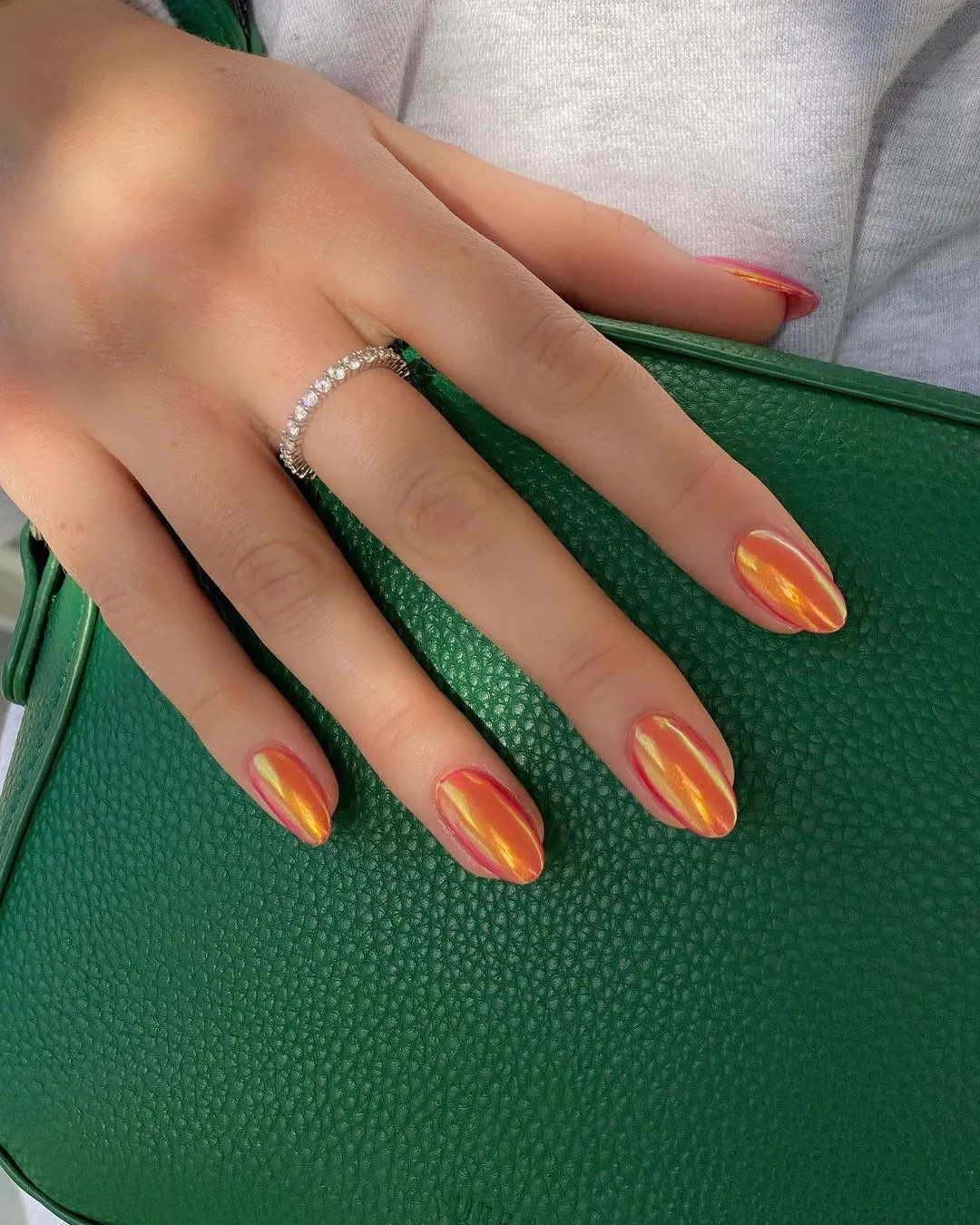 pumpkin spice glazed donut nails with glossy chrome finish touching a green bag