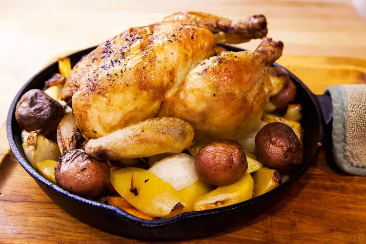 whole roasted chicken served with small potatoes in a skillet   