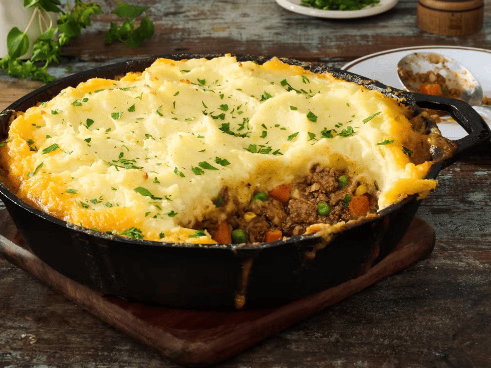 shepherd's pie topped with mashed potatoes and herbs in a cast iron skillet   