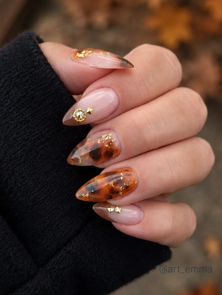almond nails featuring amber tortoiseshell art with gold foil flakes and gold studs