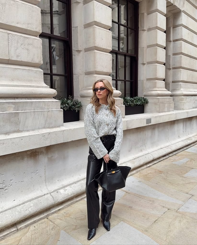 woman wearing a grey knit cardigan, black leather pants, and black heels