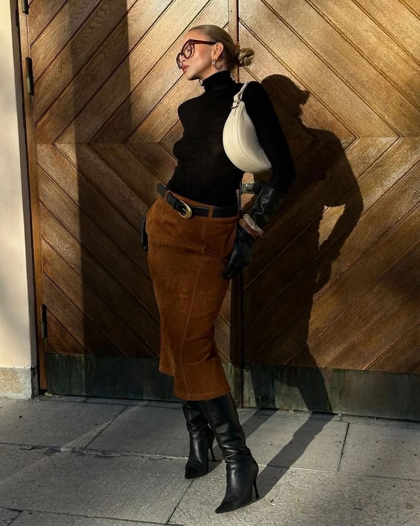 woman wearing a black turtleneck sweater, brown suede skirt, and black boots