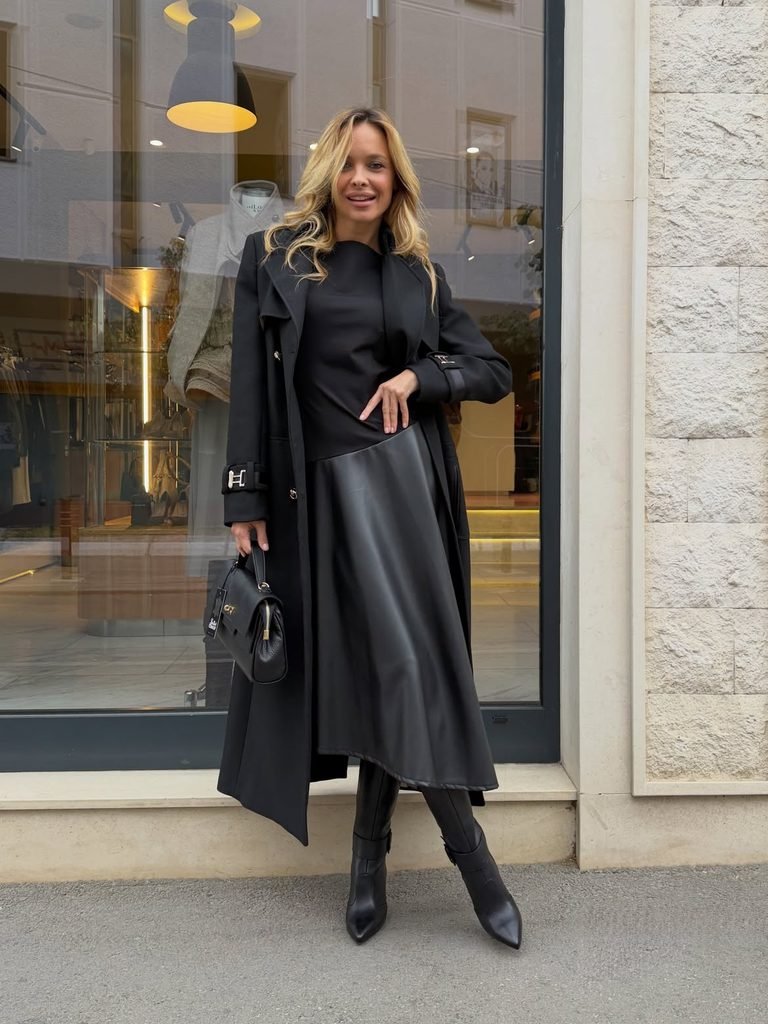 woman wearing a black trench coat, black leather skirt, and knee high boots