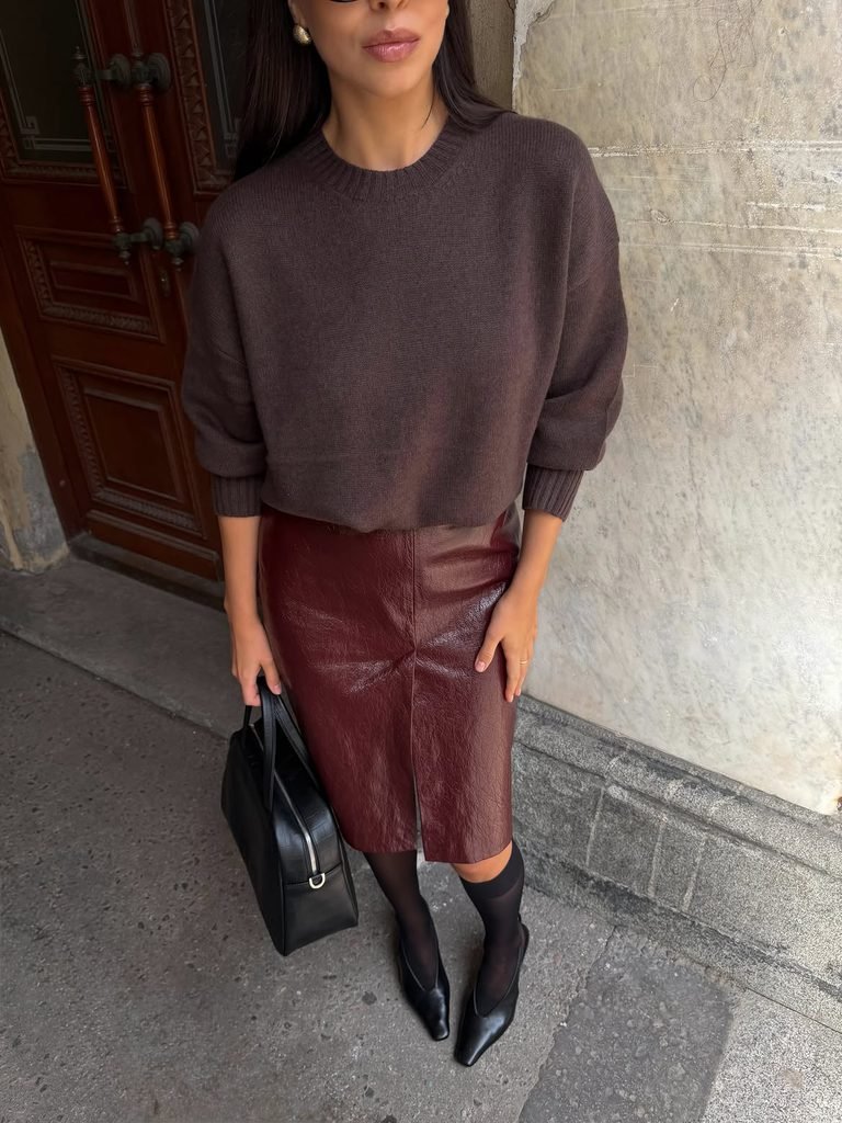 woman wearing a brown knit sweater, burgundy leather skirt, and black heels