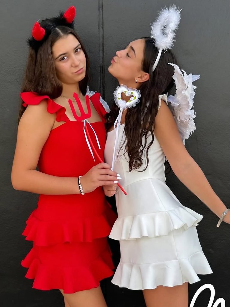 two young women wearing matching devil and angel costumes with wings and halo