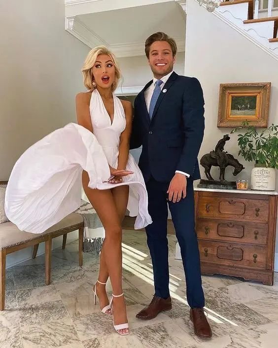 woman in a white dress and man in a suit dressed as marilyn monroe