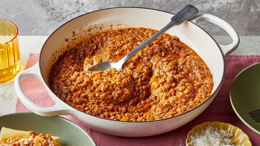 hearty mushroom and lentil ragu simmering in a white shallow Dutch oven   