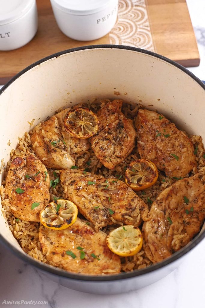 one pot lemon chicken and rice topped with charred lemon slices in a pot   